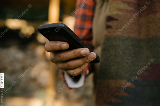 Black hand holding smartphone outdoors