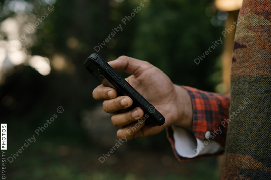 Black hand holding smartphone outdoors