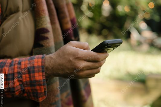 Black man holding smartphone in backyard in fall