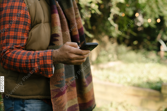 Black man holding smartphone in backyard in fall