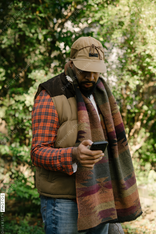 Black man holding smartphone in backyard in fall