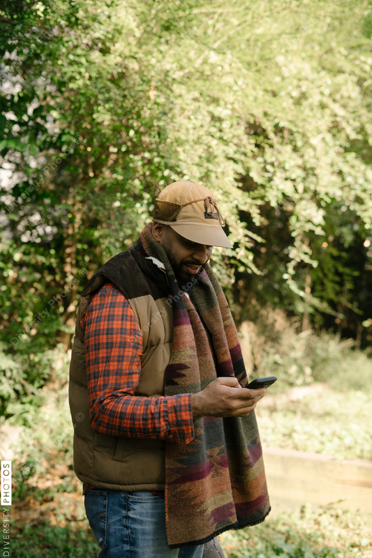 Black man holding smartphone in backyard in fall