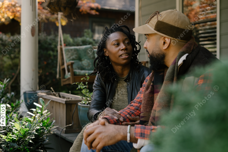 Beautiful black couple talking on front porch at home
