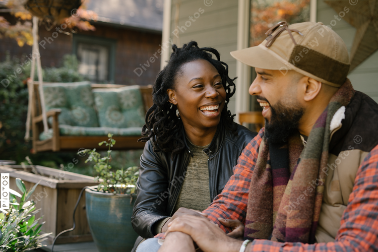 Beautiful black couple talking on front porch at home