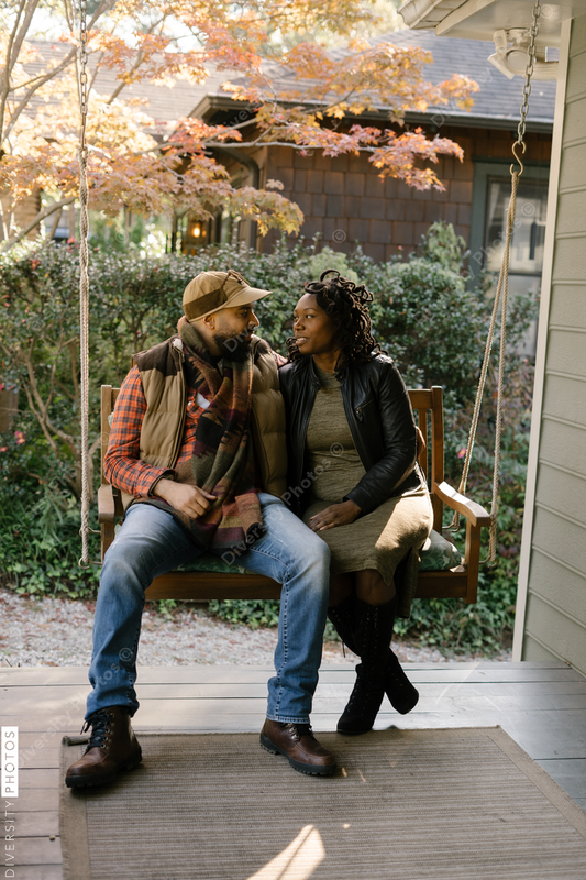 Black couple spending quality time together on front porch swing at home