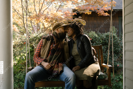 Black couple spending quality time together on front porch swing at home