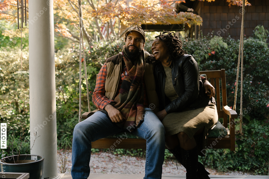Black couple spending quality time together on front porch swing at home