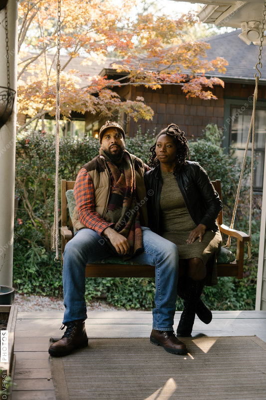 Black couple spending quality time together on front porch swing at home