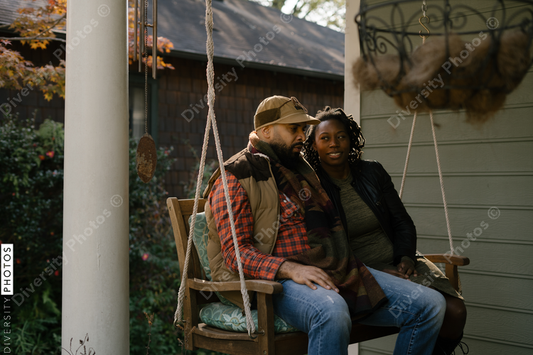 Black couple spending quality time together on front porch swing at home
