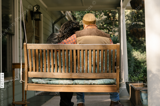 Black couple spending quality time together on front porch swing at home