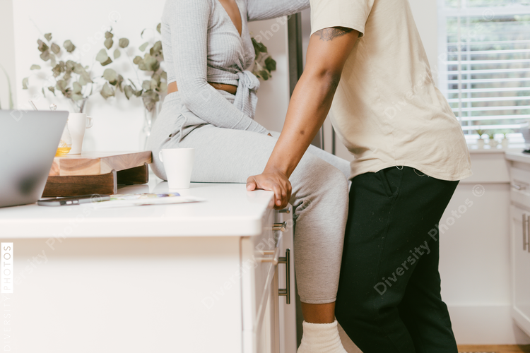 Woman sitting on counter in kitchen with boyfriend close