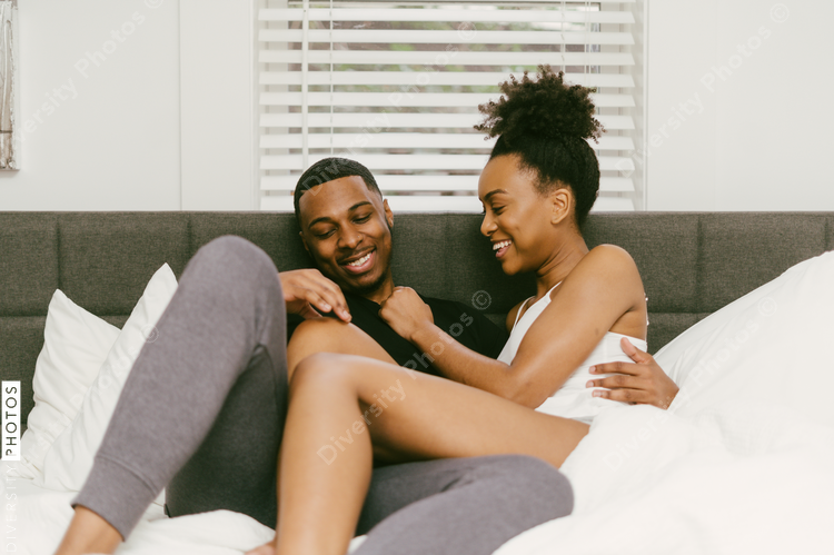 Black couple relaxing on bed at home, love connection