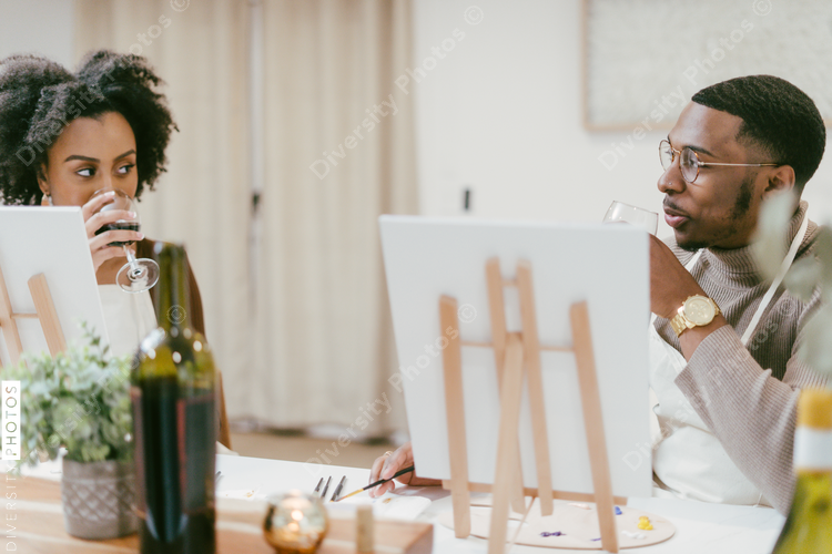 Black couple drinking wine during painting date night