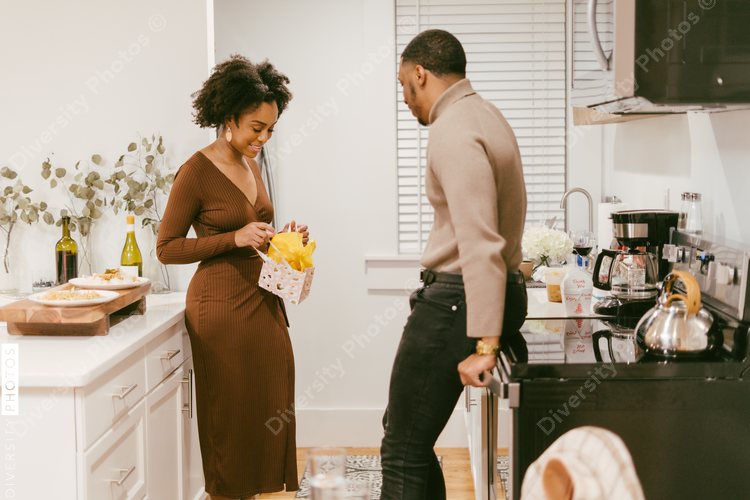 Couple celebrating anniversary at home, exchange gifts