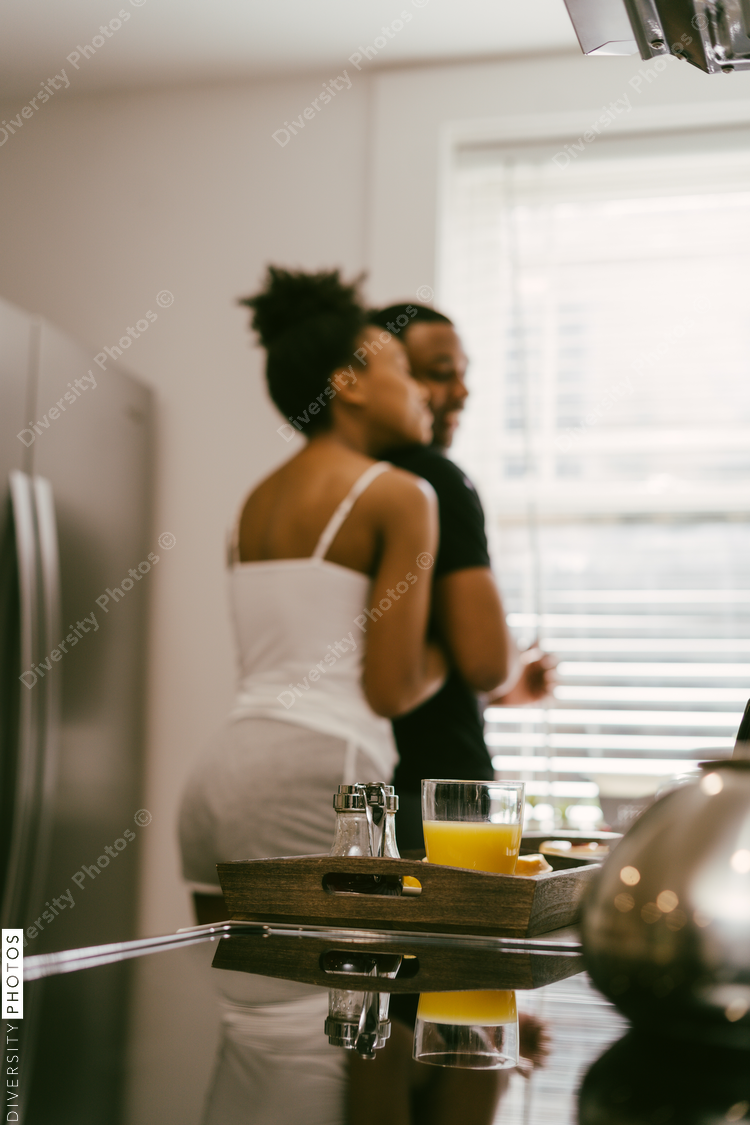 Happy, affectionate Black couple hugging in kitchen