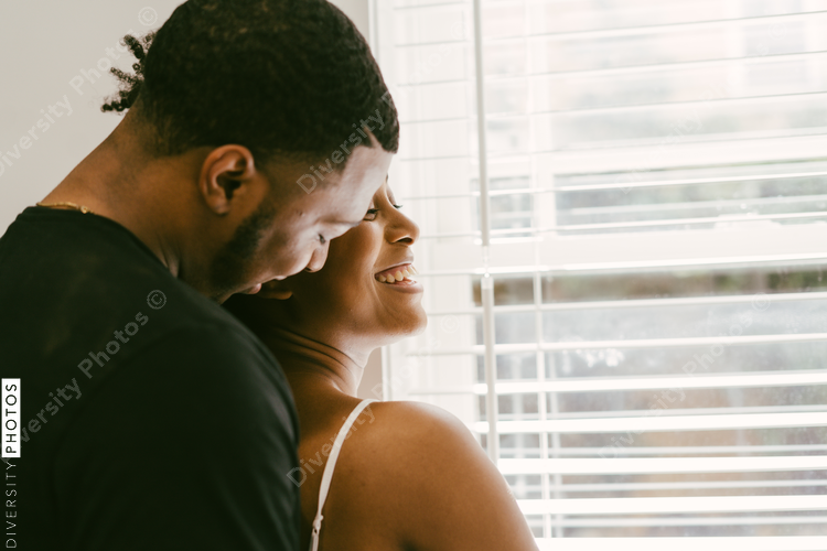 Happy, affectionate African American couple hugging in kitchen