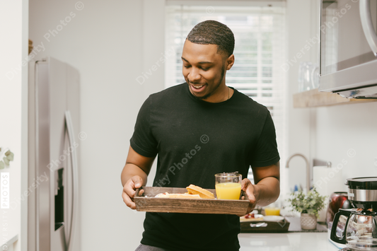 Black man bringing breakfast to girlfriend in bed at home