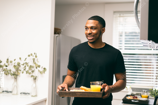 Black man bringing breakfast to girlfriend in bed at home