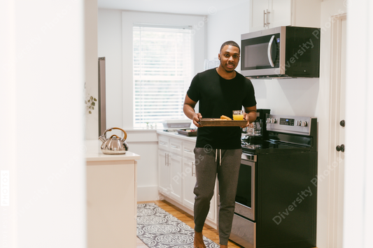 Black man bringing breakfast to girlfriend in bed at home