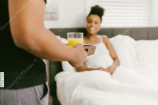 Black man bringing breakfast to girlfriend in bed at home