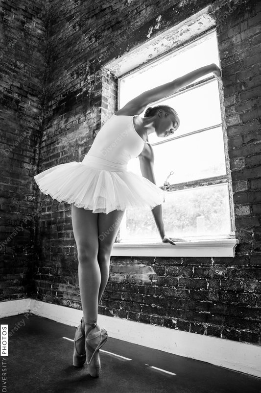 Black ballerina doing powerful ballet dance pose, wearing pointe shoes and white tutu