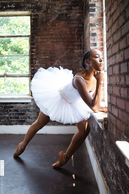 Black ballerina doing powerful ballet dance pose, wearing pointe shoes and white tutu