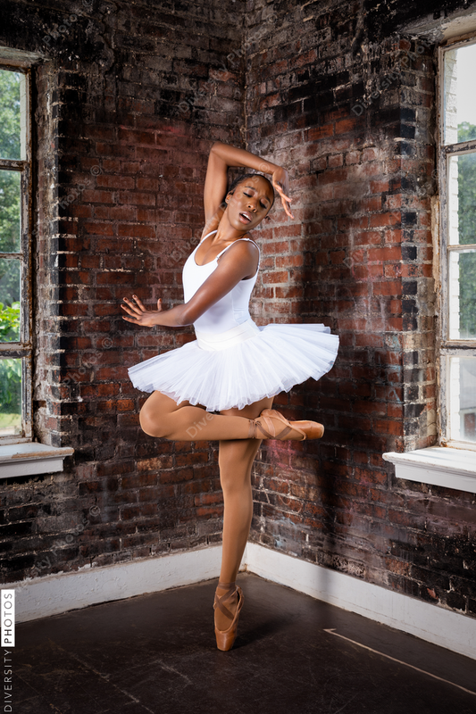 Black ballerina doing powerful ballet dance pose, wearing pointe shoes and white tutu