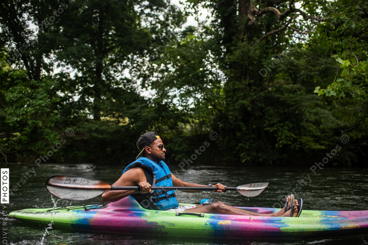 Man kayaking on river surrounded with trees