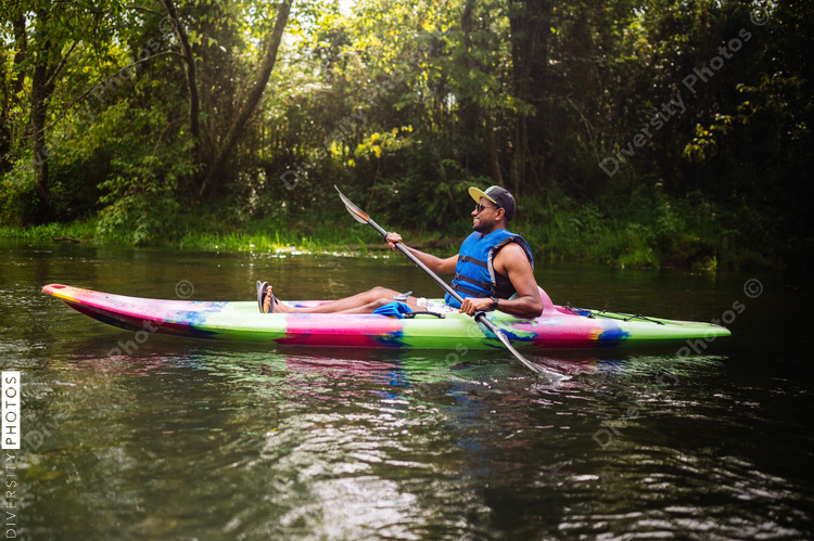 Man kayaking on calm river in colorful kayak