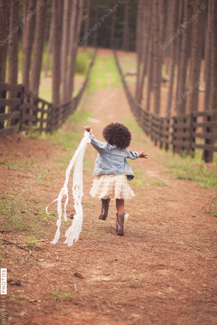 Rear view of little girl running down path with streamers
