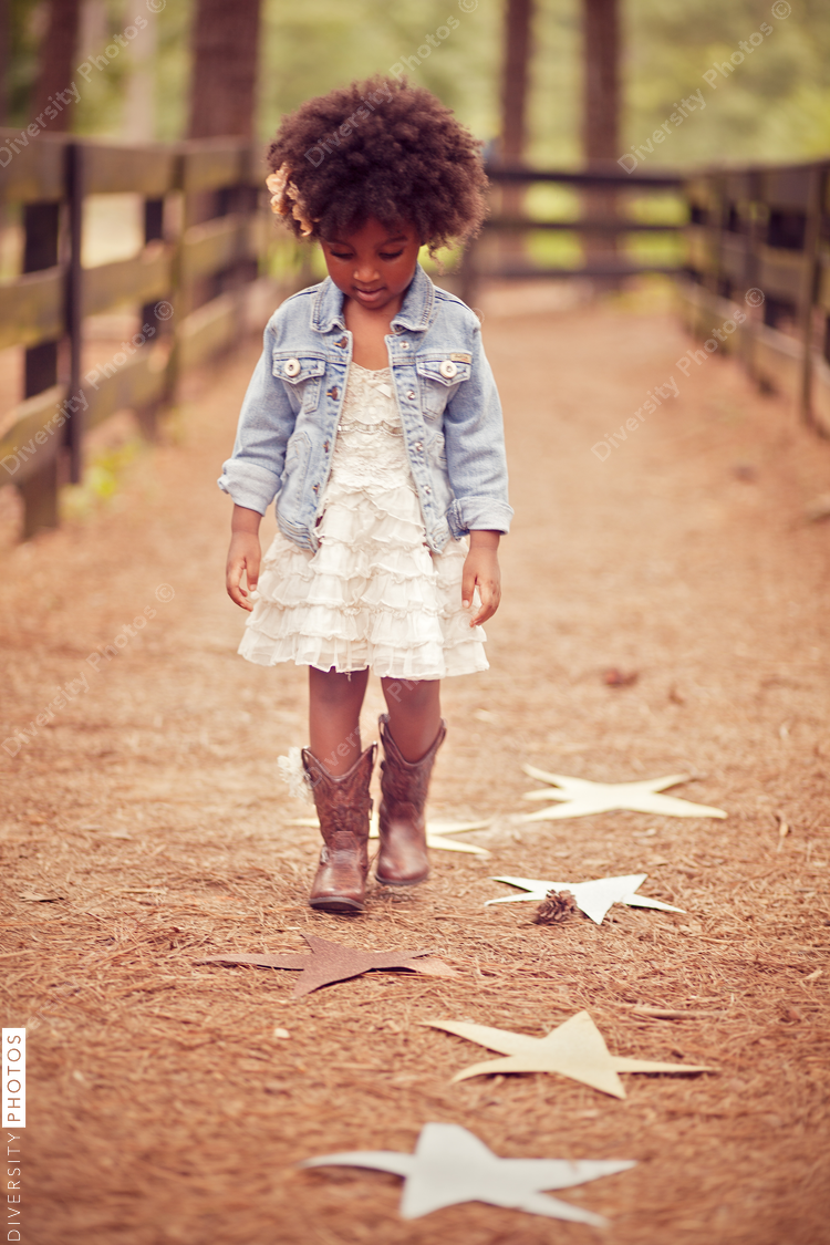 Little girl looking down at paper stars on pathway
