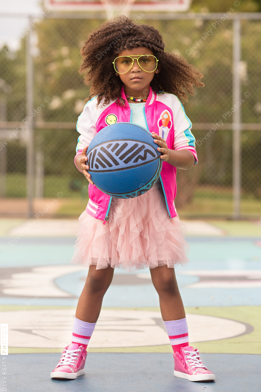 Young girl poses on playground with basketball and tutu