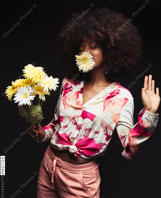 Young woman holding flower bouquet against black background