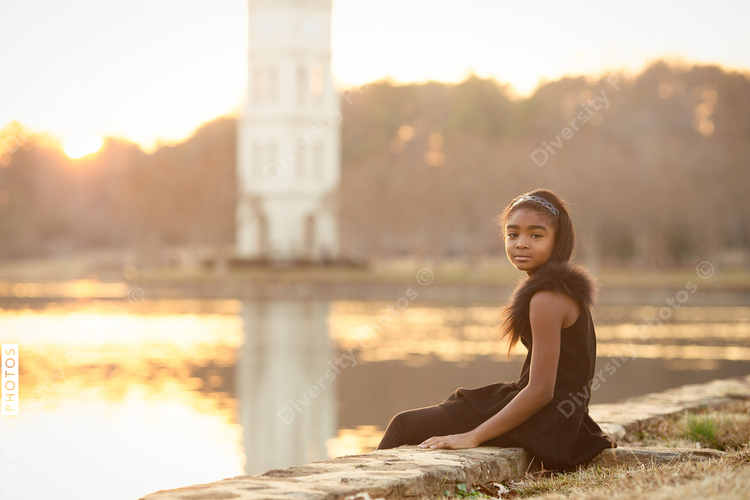 Portrait of girl sitting near lake during sunset