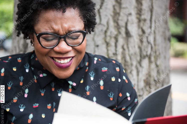 Close up of smiling woman holding book outdoors