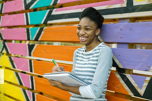 Young Black female teenager drawing in notebook at school