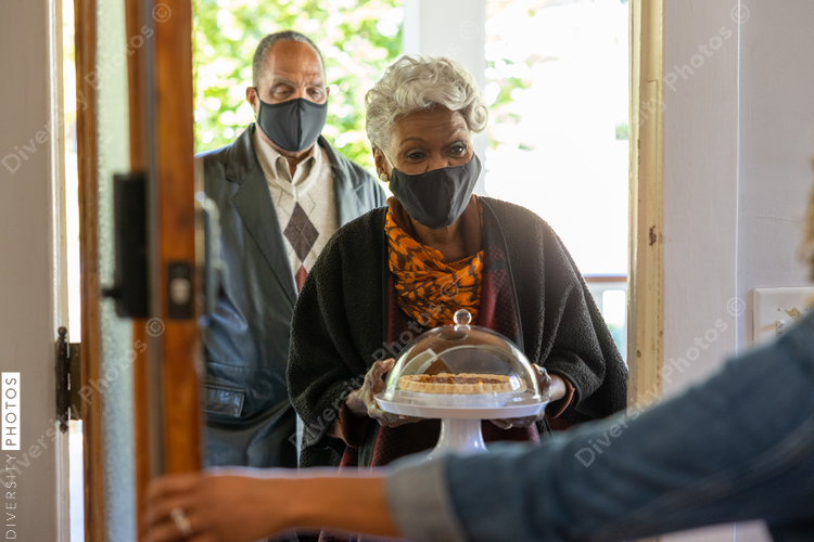 Grandmother and grandfather greet family for Thanksgiving wearing mask