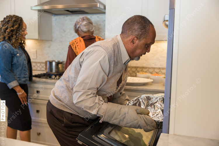Grandfather cooking turkey in oven for Thanksgiving