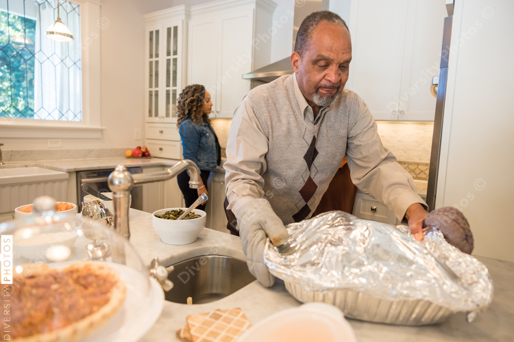 Black granddad preparing turkey for Thanksgiving dinner