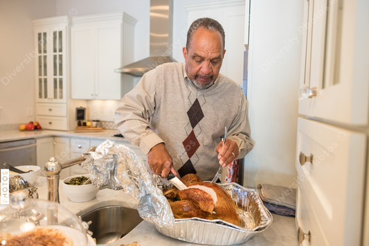Black granddad preparing turkey for Thanksgiving dinner