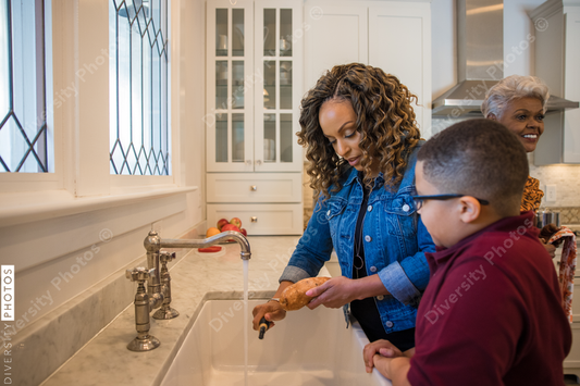 Black mother peeling potato with son in kitchen