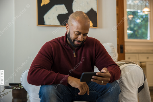Black man watching sports on smartphone before thanksgiving dinner