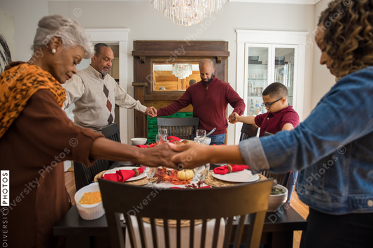 Black multigenerational family praying and blessing the food for Thanksgiving holiday meal