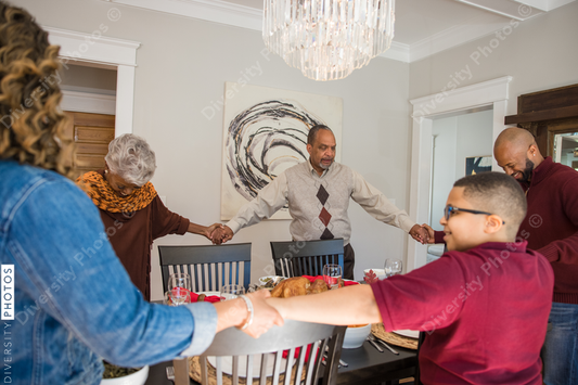 Black multigenerational family praying and blessing the food for Thanksgiving holiday meal