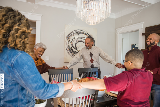 Black multigenerational family praying and blessing the food for Thanksgiving holiday meal