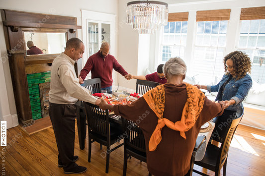 Black multigenerational family praying and blessing the food for Thanksgiving holiday meal