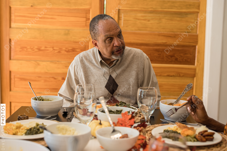 Multigenerational black family eating Thanksgiving dinner together at dining room table