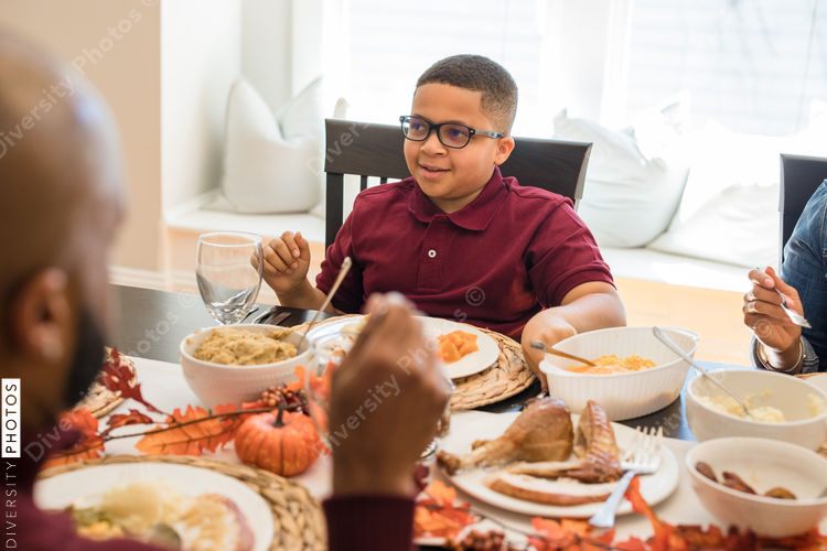 Multigenerational black family eating Thanksgiving dinner together at dining room table