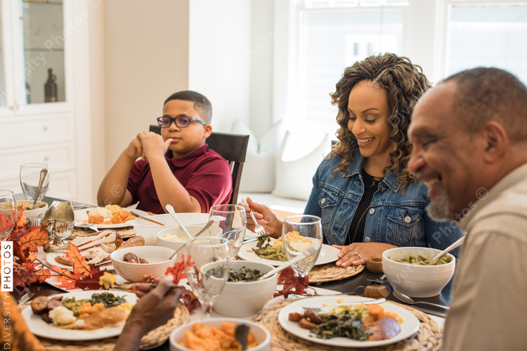 Multigenerational black family eating Thanksgiving dinner together at dining room table