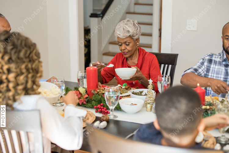 Black family eating Christmas dinner together at dining room table